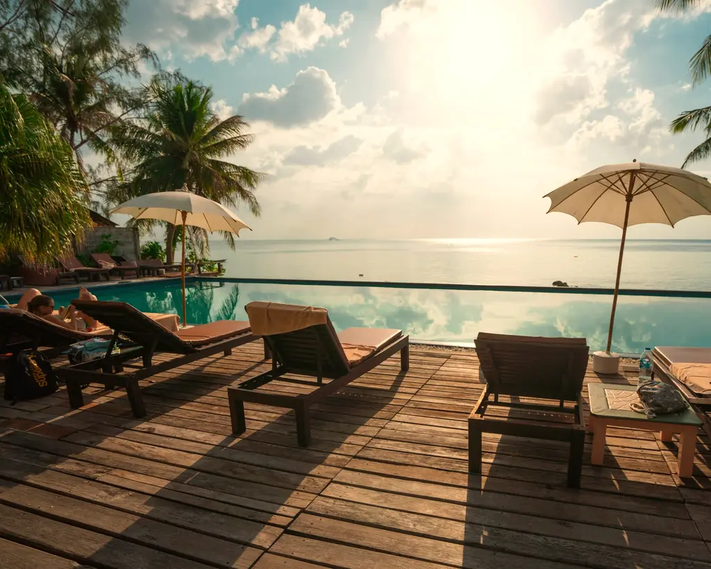 Wooden lounge deck beneath palms overlooking the sea